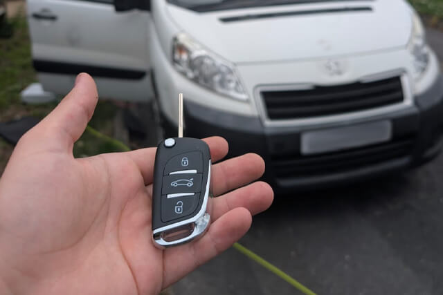 Auto locksmith showing new car key cut for a Peugeot van