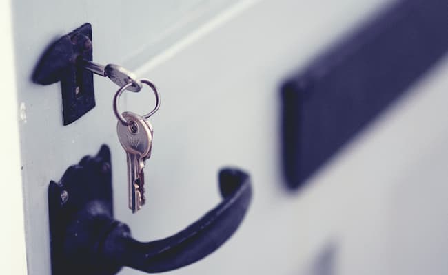 A key is stuck in a white farmhouse door.