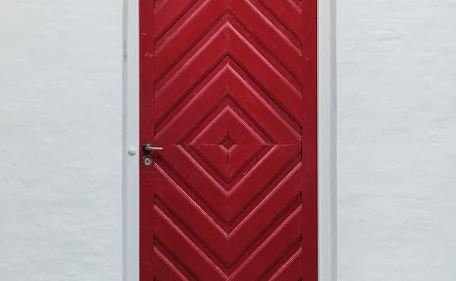 A red front door with square shapes carved into it.